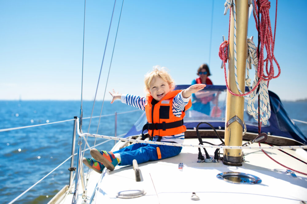 Little boy in safe life jackets enjoy sailing 