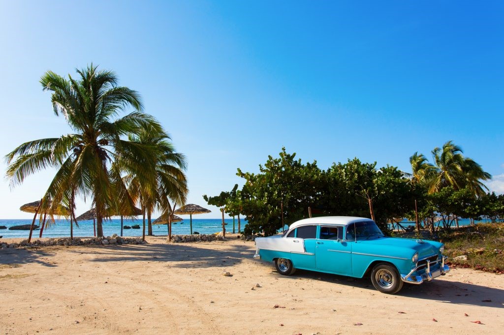 Blue car parked on a beach in Cuba