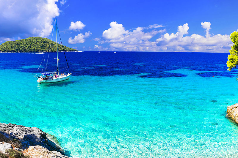 Beautiful sailing yacht near picturesque seacoast. Assos village Mediterranean  Sea, Greece. Summer vacation on Greek Island Stock Photo - Alamy