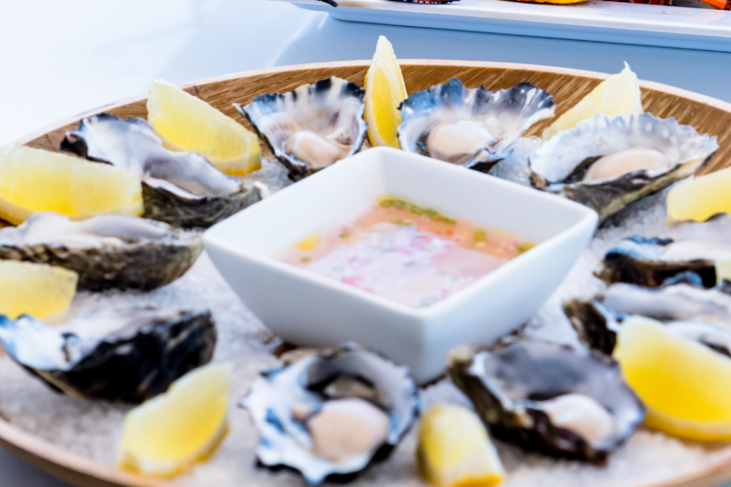 oysters served on a plate with lemons and souce