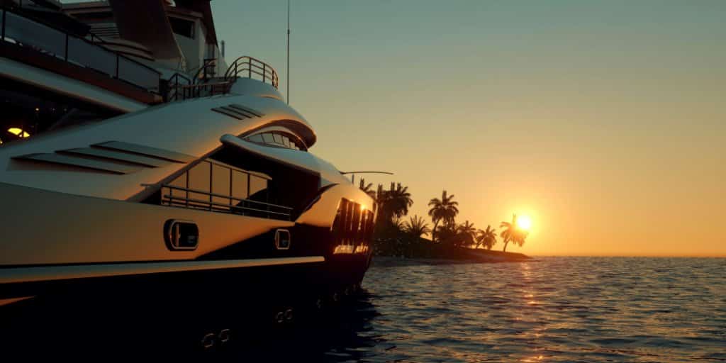 Luxury yacht sailing in front of palm trees and the sunset