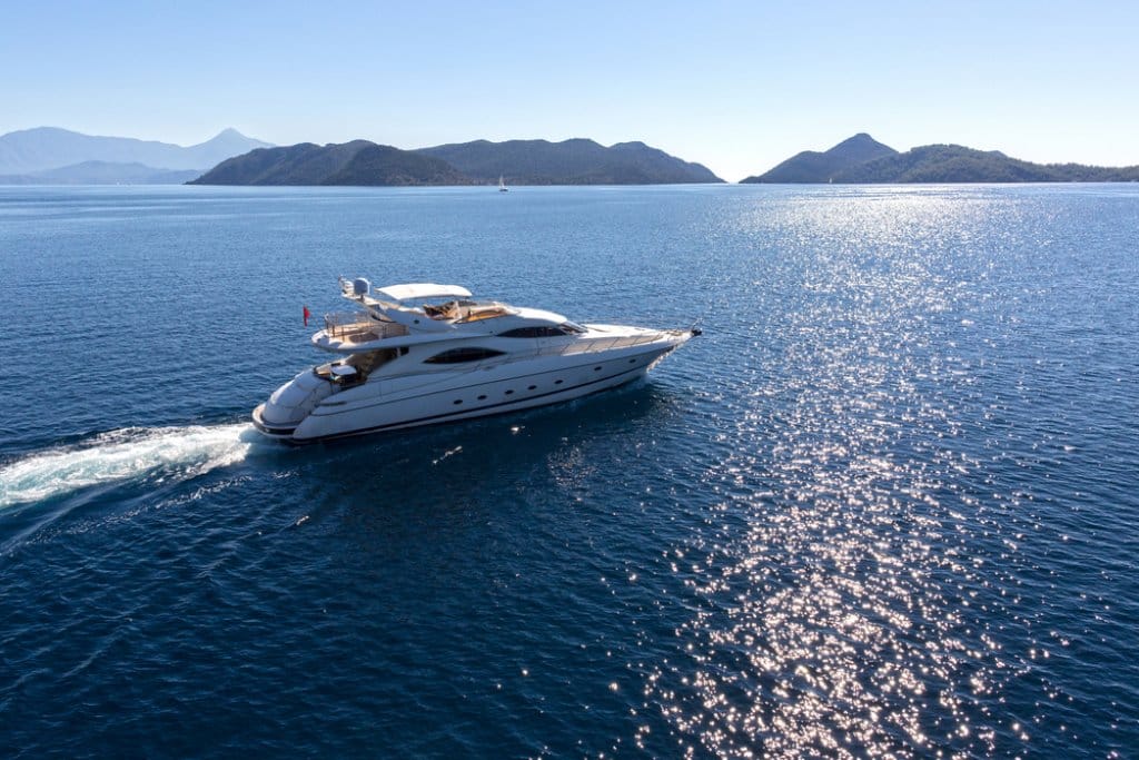 Luxury yacht sailing in bright blue ocean with mountain in background